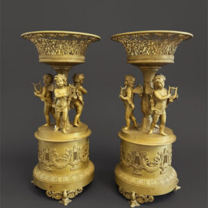 Coppia di raffinate alzate in bronzo dorato al mercurio con figure di putti musicanti